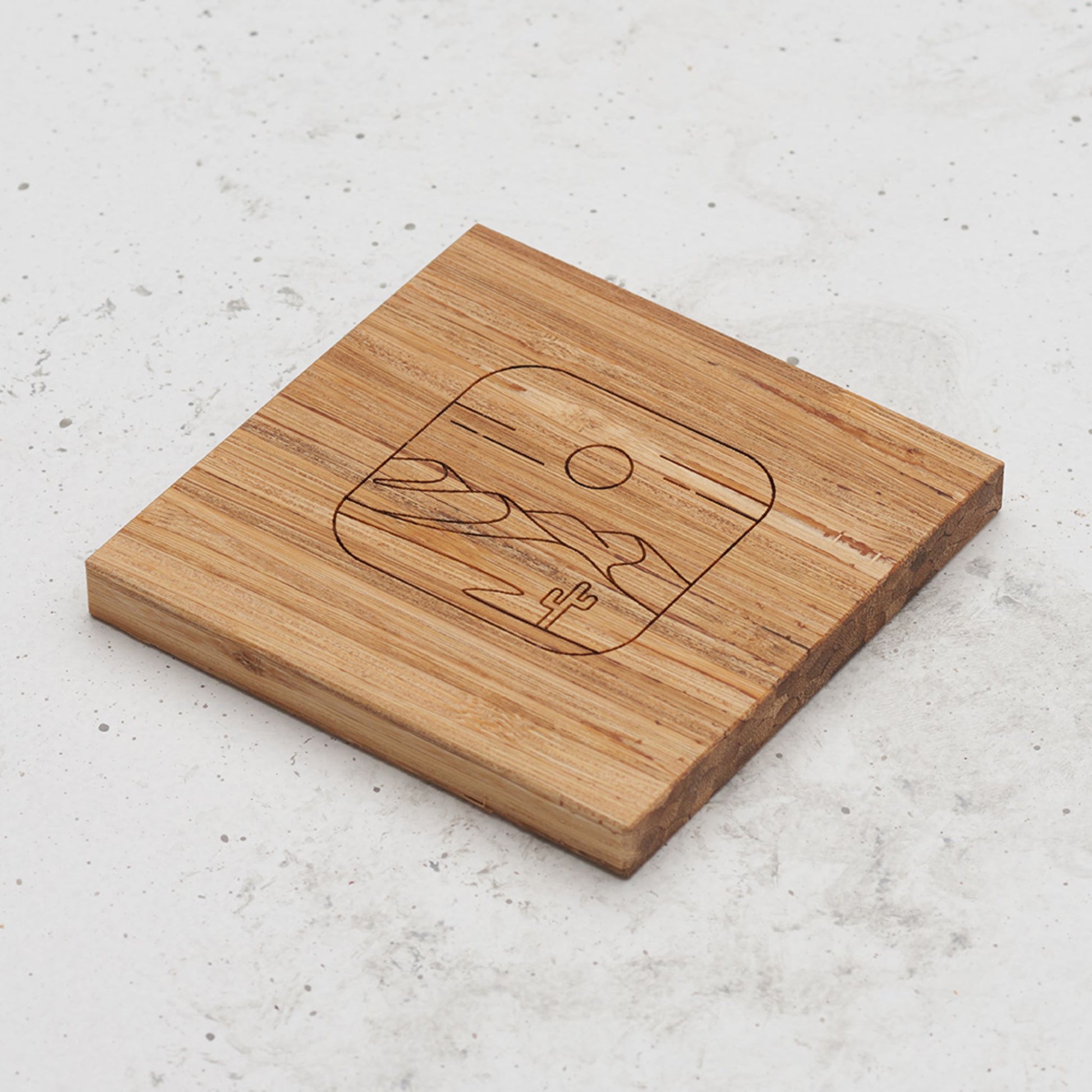 An overhead view of one of the all day every day coasters with an engraved image of the desert in the middle