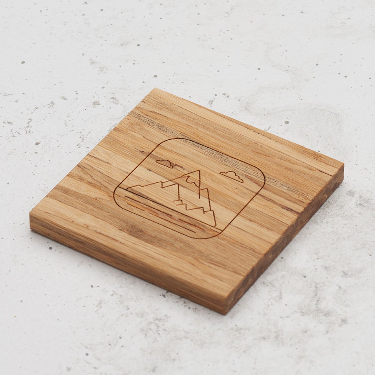 An overhead view of one of the all day every day coasters with an engraved image of a mountain in the middle