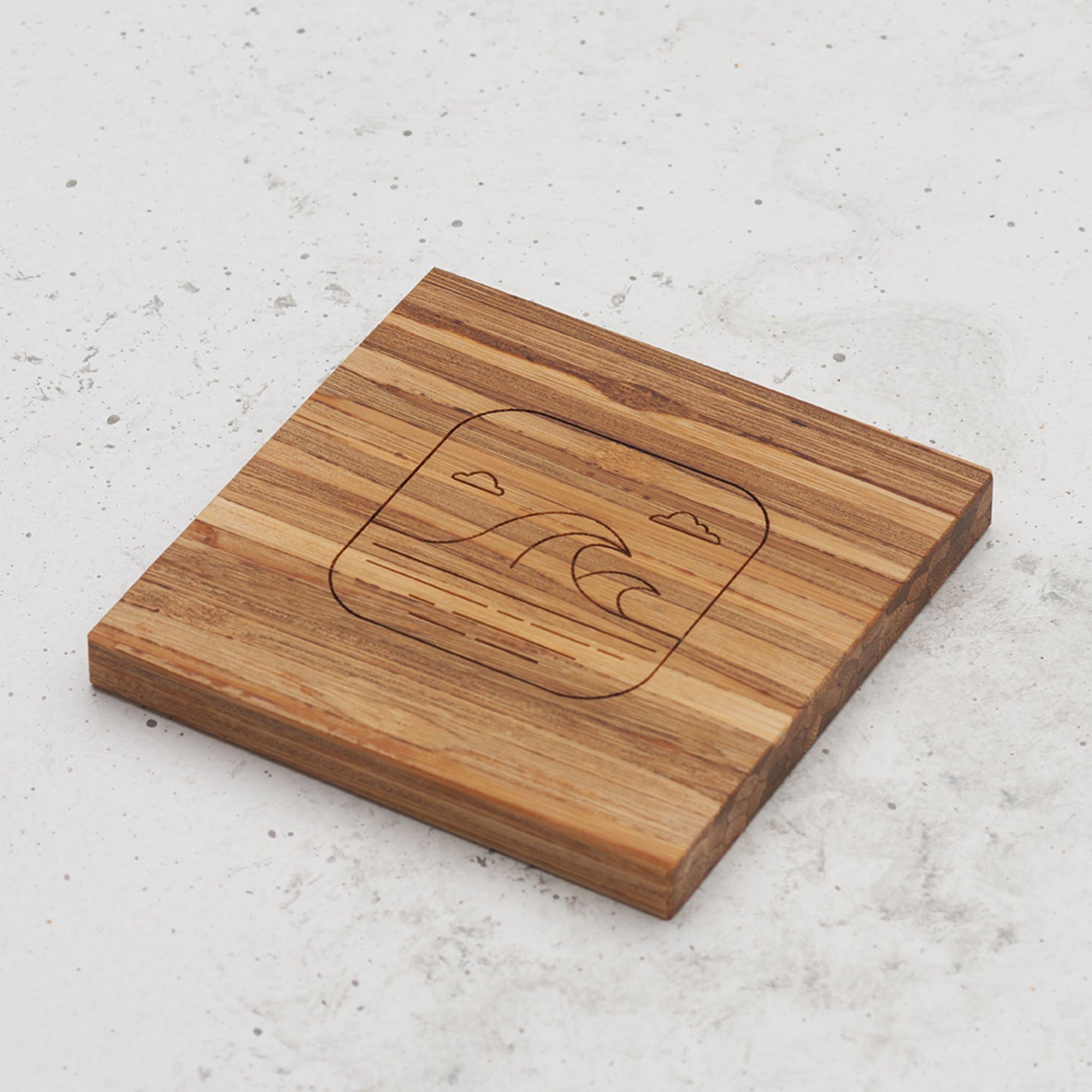 An overhead view of one of the all day every day coasters with an engraved image of the ocean in the middle