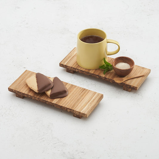 two heyday breakfast trays sitting on the countertop, one with a coffee mug, a small bowl of sugar, and a mini spoon on top, another with two biscuits on top