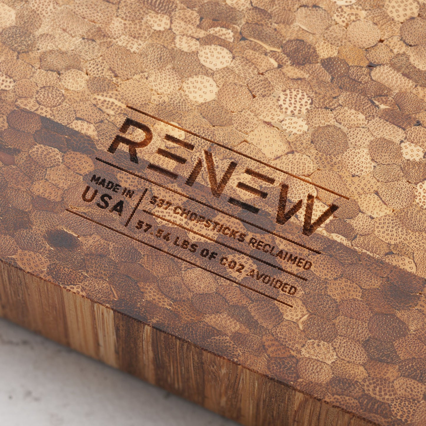 Close up view of the stamp on the back of the board that reads renew made in the usa five hundred and thirty seven chopsticks reclaimed and fifty seven point fifty four pounds of co2 avoided