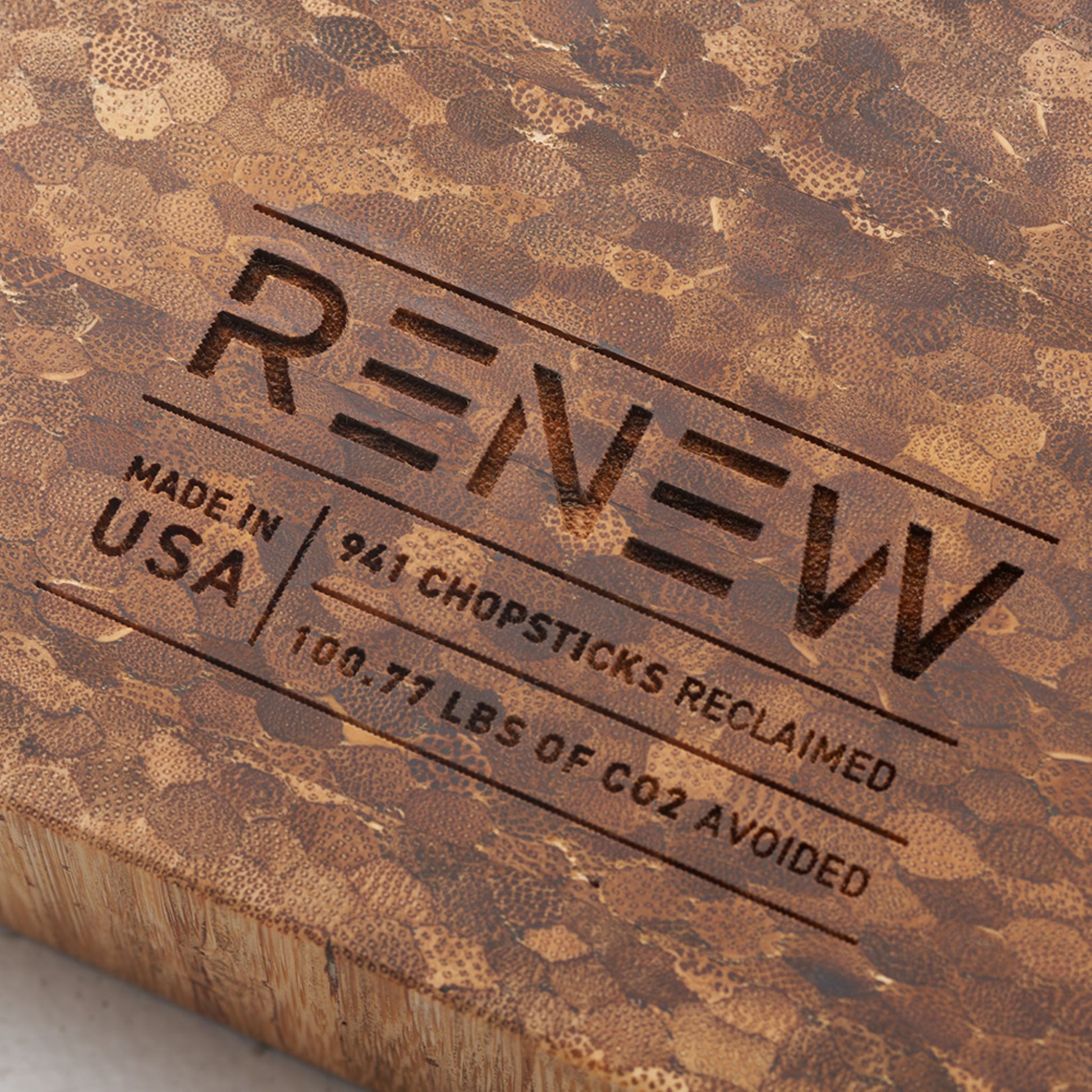 Close up view of the stamp on the back of the board that reads renew made in the usa nine hundred and forty one chopsticks reclaimed and one hundred point seventy seven pounds of co2 avoided