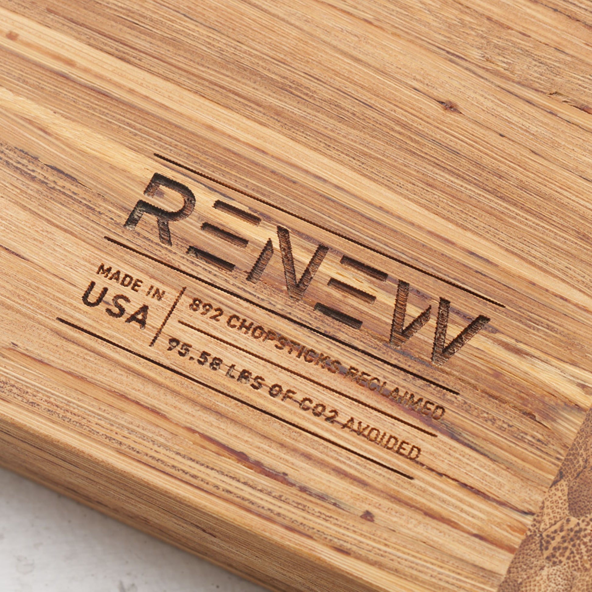 Close up view of the stamp on the back of the board that reads renew made in the usa eight hundred and ninety two chopsticks reclaimed and ninety five point five eight pounds of co2 avoided