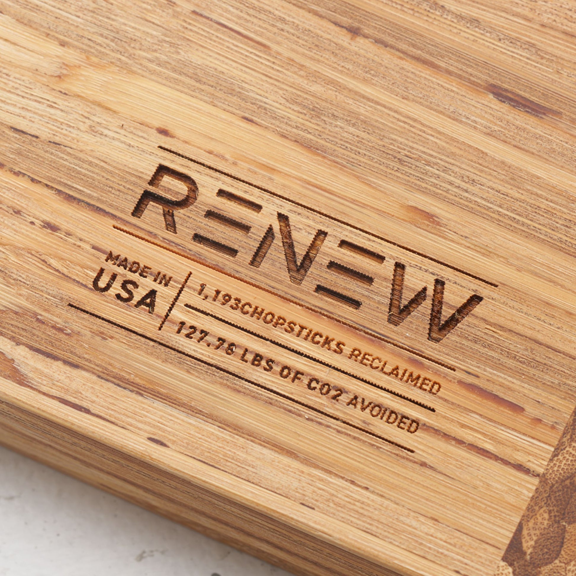 Close up view of the stamp on the back of the board that reads renew made in the usa one thousand one hundred and ninety three chopsticks reclaimed and one hundred and twenty seven point seventy six pounds of co2 avoided