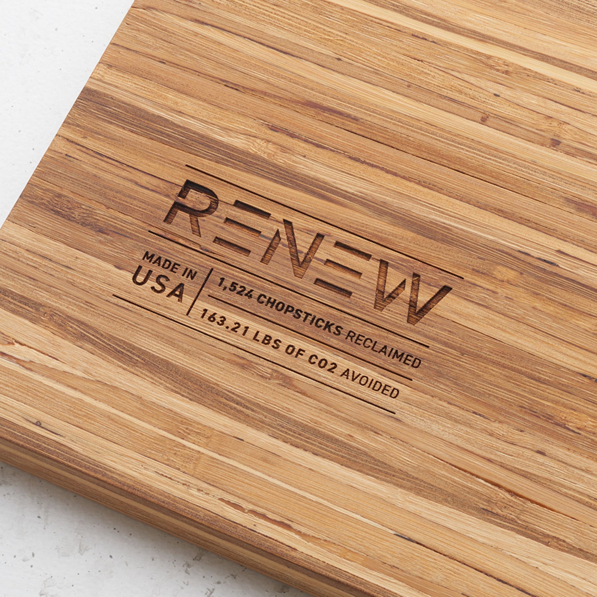 Close up view of the stamp on the back of the board that reads renew made in the usa one thousand five hundred and twenty four chopsticks reclaimed and one hundred and sixty three point twenty one pounds of co2 avoided