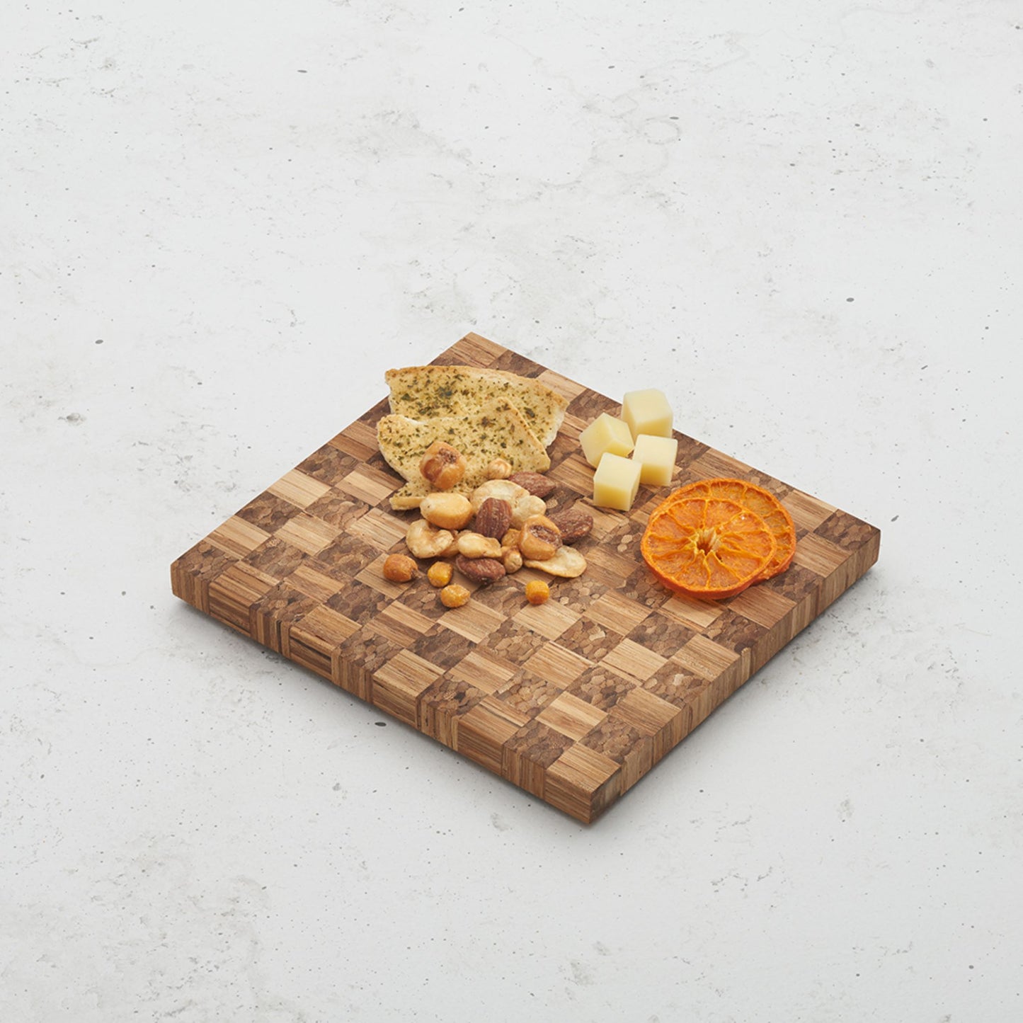Overhead view of the checkered pattern on the game night snack board with cheese and crackers sitting on top next to some dried orange slices