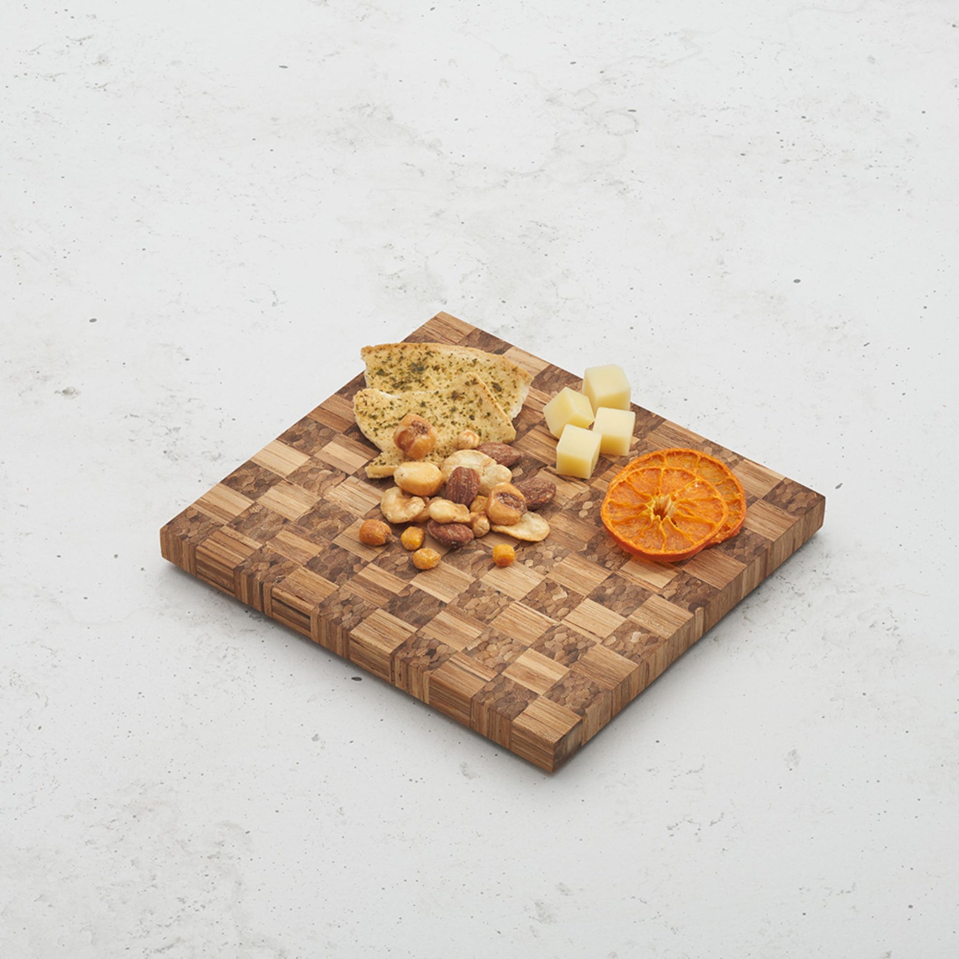 Overhead view of the checkered pattern on the game night snack board with cheese and crackers sitting on top next to some dried orange slices