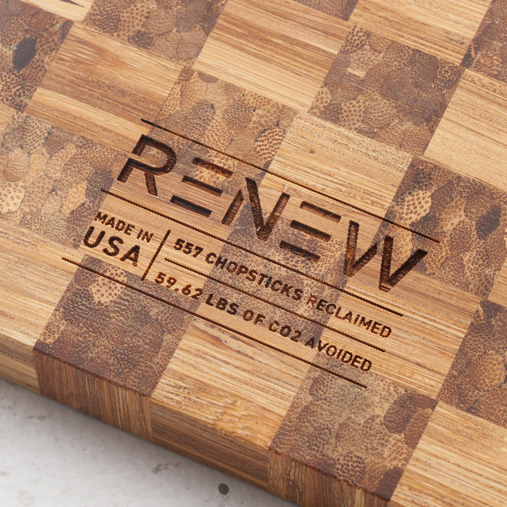 Close up view of the stamp on the back of the board that reads renew made in the usa, five hundred and fifty seven chopsticks reclaimed and fifty nine point sixty two pounds of co2 avoided