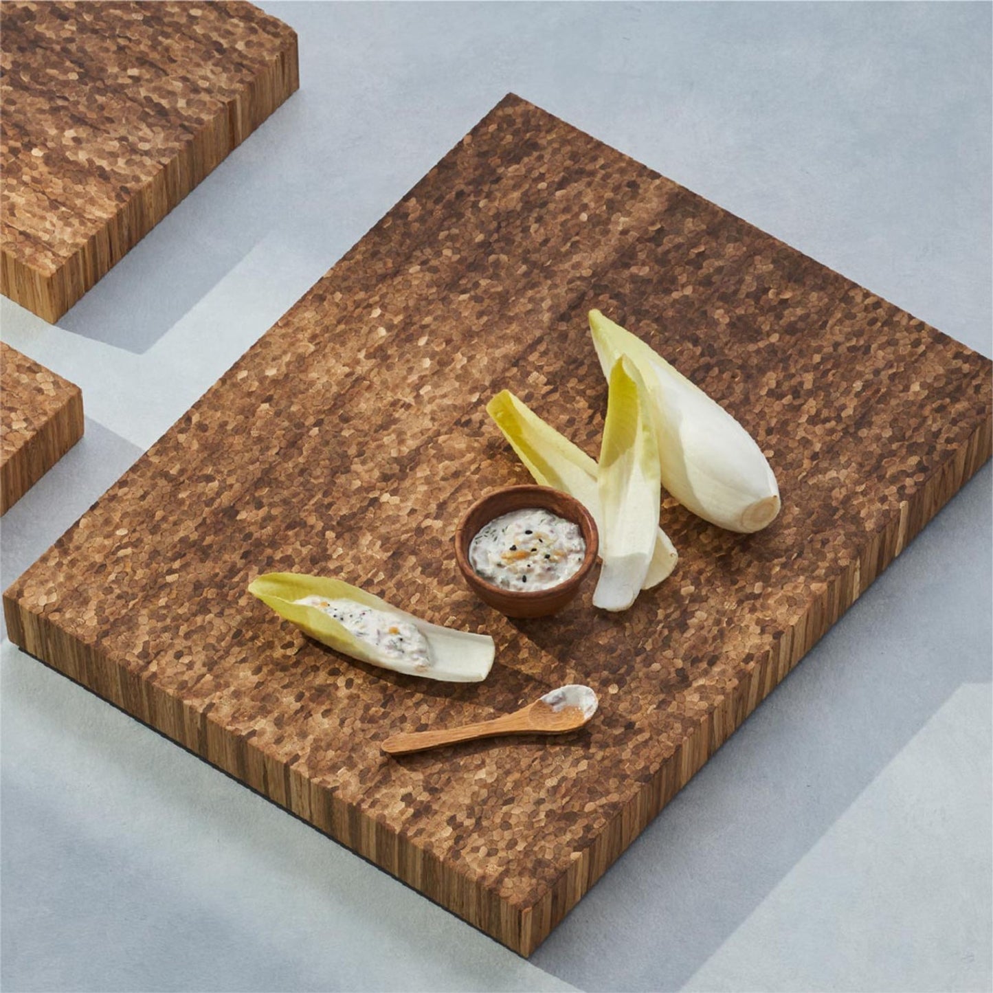 several pieces of vegetable with a small bowl of dipping sauce on the bread board