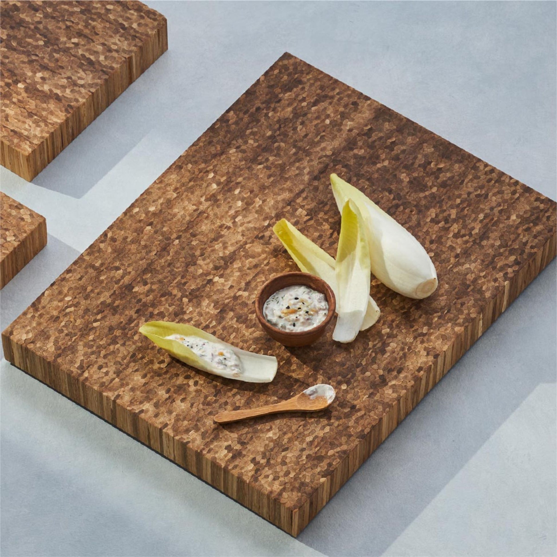 several pieces of vegetable with a small bowl of dipping sauce on the bread board