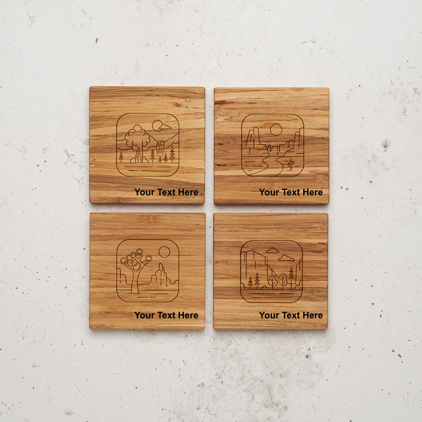 An overhead view of all four of the road trip themed all day every day coasters sitting next to each other on a counter. Each coaster is engraved with a minimalist, line-art illustration of a nature scene (including a waterfall, a desert canyon, a Joshua tree, and a forest) with the placeholder text "Your Text Here" below the artwork.