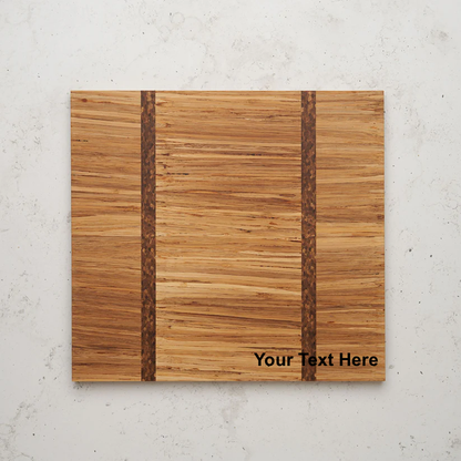 Overhead view of the Large Gather and Graze serving board. A close-up photograph features a square wooden cutting board made of light-colored, horizontally-grained wood, with two vertical inlays of darker, braided-looking wood. The lower right corner has placeholder text that reads "Your Text Here."