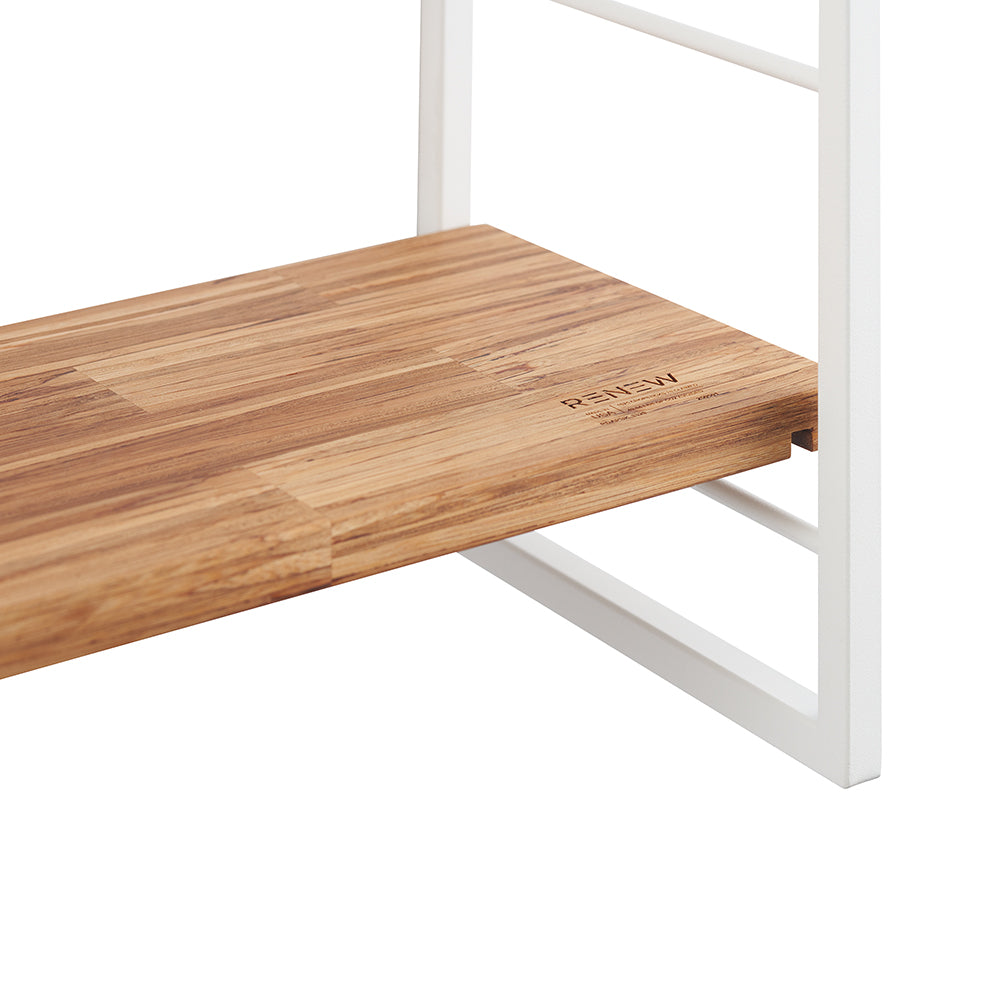 Close-up of a light brown, vertically slatted wooden shelf resting on a white metal frame. The word "RENEW" is lightly engraved on the front right corner of the shelf.